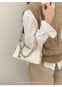Close-up of cream chain handbag with silver heart pendant and smooth leather texture