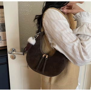 Borsa a mezzaluna marrone scuro con ciondolo a pompon indossata da una modella