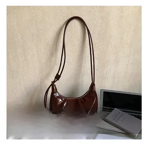 Detail showing brown patent leather hobo bag with stitched pleats and decorative knot