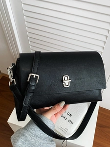 Minimalist black rectangle flap bag with silver metal turn-lock and adjustable strap