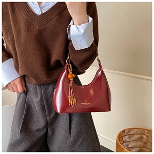 Detail of burgundy hobo bag with glossy finish and wooden bead fringe accessory