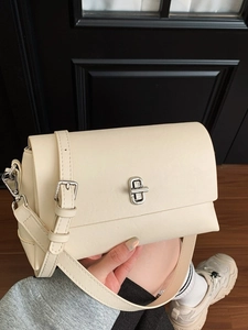 Minimalist cream crossbody bag with silver twist lock and adjustable shoulder strap