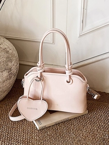 Light pink handbag with heart coin purse and knot handle on a textured rug