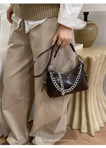 Detail of retro chocolate brown underarm bag with silver chain and heart charm
