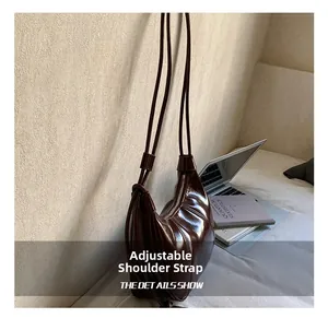 Detail of adjustable strap and chocolate brown oil wax leather on crescent shoulder bag