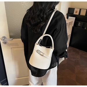 Detailed view of a white leather bucket bag with metal buckle and shoulder strap