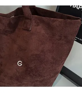 Close-up of soft brown suede tote bag with BAG lettering and high-quality texture