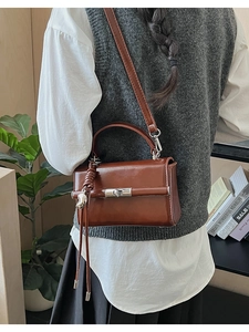 Detail view of a vintage brown leather crossbody bag with a silver rotating metal lock