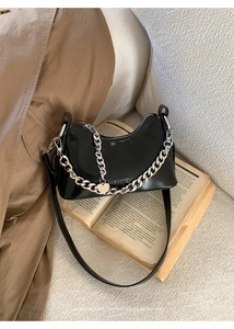 Macro shot of black gloss oil wax leather shoulder bag with silver chain and heart tag