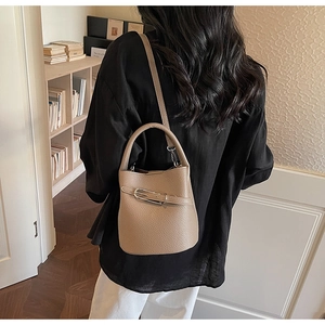 Detail of tan lychee pattern leather bucket bag with silver buckle on a stylish shoulder strap