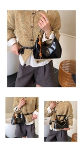 Détail du sac croissant noir avec logo doré et pendentif à pompon en perles de bois