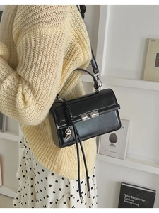 Detail of black matte leather handbag with silver twist lock and braided side ornament