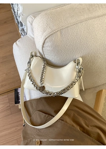 Detail of a creamy white crescent bag with glossy oil wax leather and silver chain strap