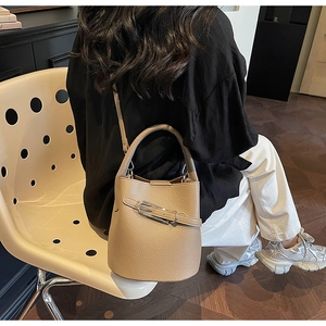 Détail du sac seau en cuir grainé beige avec boucle argentée et bandoulière réglable