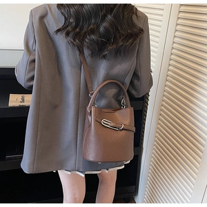 Détail du sac seau en cuir grainé marron foncé avec boucle argentée et bandoulière