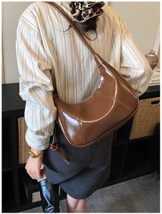 Detail of dark brown glossy patent leather crescent bag with geometric stitching on strap