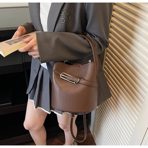 Détail du sac seau en cuir marron avec motif litchi et boucle métallique argentée