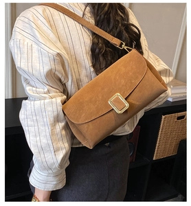 Détail d'un sac bandoulière marron avec boucle dorée porté par un mannequin