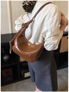 Detail of the brown glossy leather hobo bag featuring a unique knotted shoulder strap