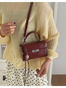 Detail of burgundy glossy leather handbag with silver lock and heart tassel charm