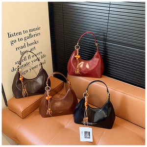 Detailed display of assorted glossy leather Hobo bags with tassel bead pendants on a sofa
