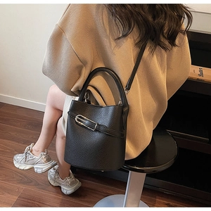 Détail du sac seau noir en cuir grainé avec boucle argentée et bandoulière réglable