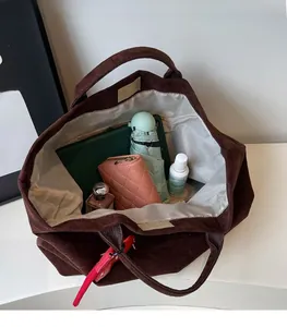 Top view of spacious dark brown suede tote bag filled with tablet and daily essentials