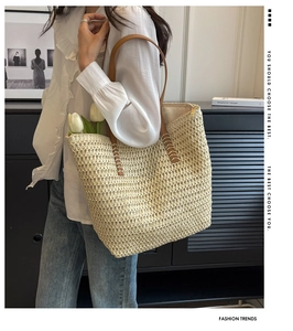 Détail de anses en cuir marron cousues main sur un sac cabas en paille avec fermeture