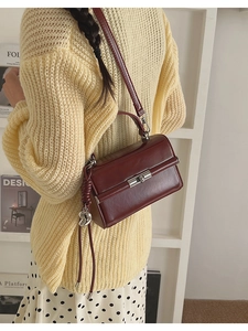 Close-up of a burgundy leather flap bag with silver heart charm and turn-lock closure