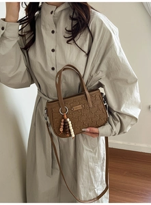 Détail d'un sac à main marron en cuir PU gaufré avec un gland en perles et une bandoulière