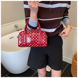 Close-up of red polka dot Boston bag featuring shiny patent leather and metallic logo detail