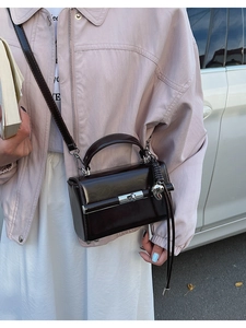 Close-up of chocolate brown glossy leather bag with silver buckle and metallic charm