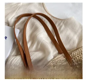Détail du sac en paille tissée avec poignées en cuir marron et fermeture éclair de plage