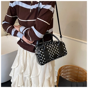 Close-up of black and white polka dot mini bowling bag with glossy finish and handle