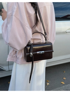 Outdoor shot of a classic brown square handbag with metal clasp and heart charm