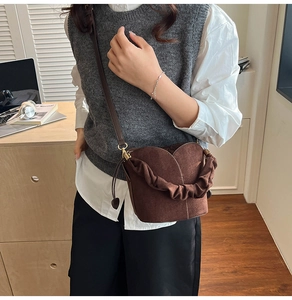 Détail du sac seau en daim marron foncé avec poignée à volants et fermeture à cordon