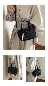 Détail du sac bandoulière noir texturé avec breloque en perles et bandoulière en cuir