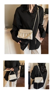 Detail of off-white pleated cloud bag with pearl handle and metal chain shoulder strap