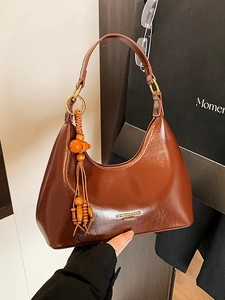 Brown faux leather hobo bag with gold hardware and a wooden bead tassel accessory