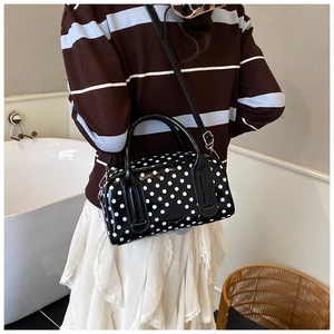 Polka dot handbag shown on model featuring sleek glossy leather and crossbody strap