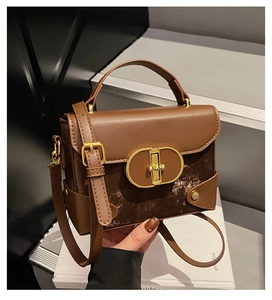 Detail of a brown two-tone box bag with smooth leather, suede panels and gold twist lock