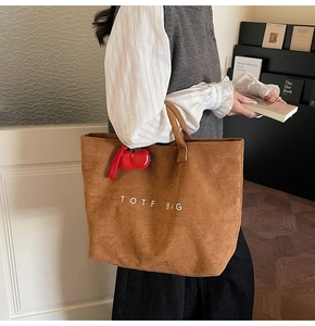 Detailed macro view of the brown suede tote bag featuring white embroidery and cherry charm