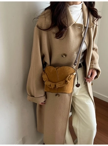 Détail du sac seau en daim avec plis en forme de pétales et breloque en cœur