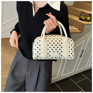 Close-up of white leather polka dot handbag with round handles and metal logo plate