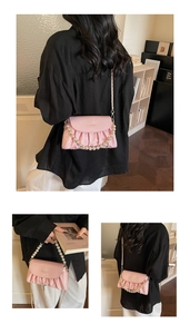 Detail of pink pleated cloud bag with pearl handle and metallic chain strap