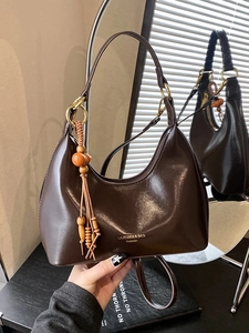 Brown vintage underarm bag in polished leather with wooden bead tassel and metal rings