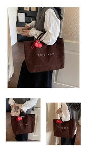 Macro detail of dark brown suede tote bag with TOTF BAG text and cherry charm