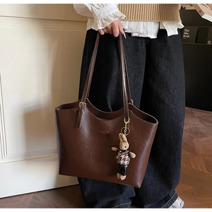 Détail d'un sac cabas en cuir marron foncé avec charm lapin et bandoulières réglables