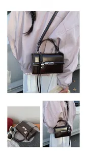Detail view of dark coffee leather handbag with silver rotary lock and heart charm