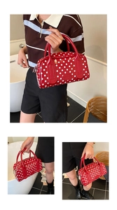 Detailed view of red polka dot handbag featuring glossy patent leather and dual handles